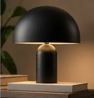 Black dome table lamp on a pale book in warm light.