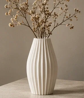 Ivory ribbed vessel with flowering branches on a neutral stone surface.